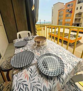 une table avec des assiettes et des bols sur un balcon dans l'établissement T2 front de mer secteur Lydia- Clim, au Barcarès