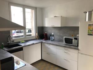 a kitchen with white cabinets and a microwave at FENUA : gite 5 chambres 10 couchages en ville in Valognes