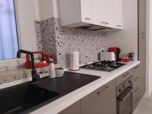 una cucina bianca con lavandino e piano cottura di Modern Central Apartment a Grottammare