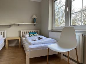 ein kleines Zimmer mit einem Bett und einem weißen Stuhl in der Unterkunft Jaardenhuug - EG in Utersum