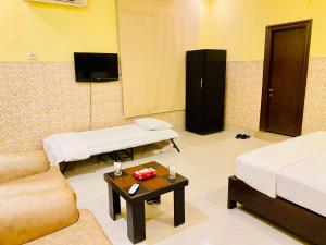 a room with two beds and a couch and a tv at HOTEL ROYAL ONE in Multan