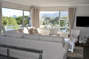 een woonkamer met een bank en een groot raam bij Ocean Pearl Hermanus - 5 Bedrooms in Hermanus