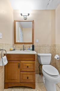 a bathroom with a toilet and a sink with a mirror at Cozy Retreat, Steps to Yale Bridgeport Hospital in Bridgeport +8 photos