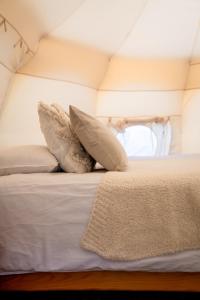 uma cama com almofadas num quarto em Glamping Gozdna Jasa em Bovec