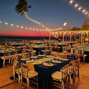 un grupo de mesas y sillas con luces y el océano en Mishol Bodas Hotel & Beach Club Privado en Acapulco