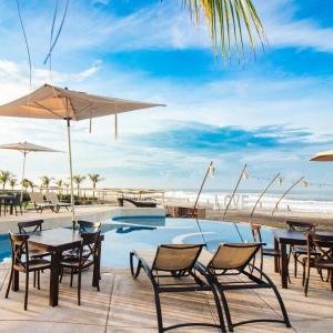 una piscina con mesas y sillas junto a la playa en Mishol Bodas Hotel & Beach Club Privado en Acapulco