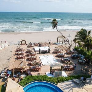 a beach with tables and chairs and the ocean at Mishol Bodas Hotel & Beach Club Acapulco Diamante in Acapulco