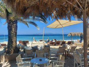 - une plage avec des chaises longues, des parasols et des personnes sur la plage dans l'établissement Green House Marathon - Greece, à Nea Makri