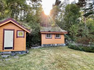 a small cabin in a yard with the sun shining at Holiday home MOSTERHAMN V in Mosterhamn