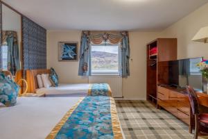 um quarto de hotel com uma cama e uma televisão de ecrã plano em Muthu Fort William Hotel em Fort William