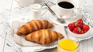 a tray with croissants and a cup of coffee and strawberries at Campolo Apartment in Reggio Calabria