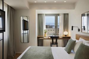 1 dormitorio con cama y escritorio con ventana en Noa Hotel en Tesalónica