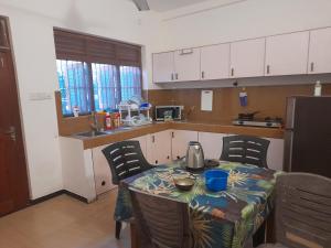 eine Küche mit einem Tisch und Stühlen sowie eine Küche mit weißen Schränken in der Unterkunft Mealanie's House in Unawatuna