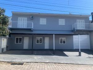 a gray house with white doors and a balcony at Apartamento Aconchegante e Silencioso em Bairro Tranquilo in Bento Gonçalves