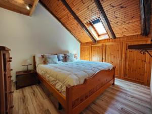 a bedroom with a large bed with a wooden ceiling at Hostdomus - Bouvier Apartment in Cesana Torinese