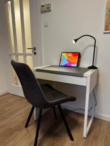 a desk with a laptop computer on it with a chair at City-Designapartment in Gaggenau
