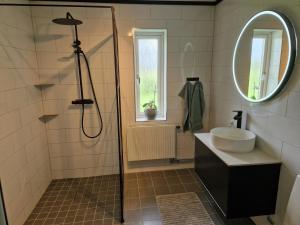 uma casa de banho com um chuveiro, um lavatório e um espelho. em Lantlig villa utanför Uppsala em Alunda