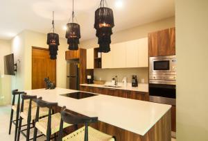 a kitchen with a white counter top and black chairs at Naj Kiin- Aldea Zama Tulum by Casago in Tulum