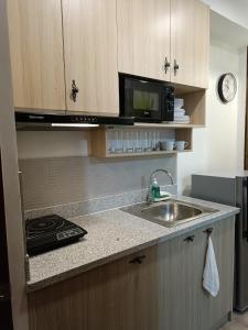 a kitchen with a sink and a microwave at 3 J's STAYCATION in Bacolod