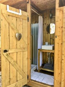 bagno con porta in legno e lavandino di Tente Glamping nature et océan, Rogil a Rogil