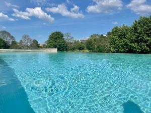 una gran piscina de agua azul con árboles en el fondo en Quinta Escondida da Avessadas, 