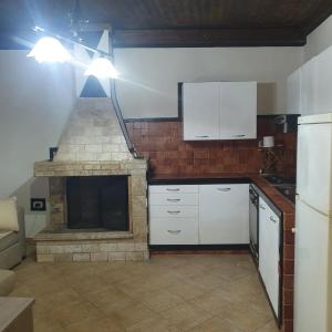 a kitchen with a stone fireplace and white cabinets at b e b bascus argius in Cagliari