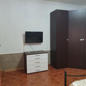 um quarto com uma televisão e uma cómoda com um armário em b e b bascus argius em Cagliari