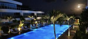 a hotel pool with chairs and palm trees at night at Dunas de Cotovelo in Parnamirim