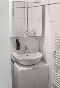 ein weißes Badezimmer mit einem Waschbecken und einem Spiegel in der Unterkunft Studio Apartment am Kurpark in Bad Segeberg