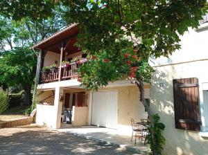 a house with a balcony with a table and chairs at Gite "Le SEQUOIA" in Corbarieu