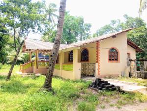 a house with a palm tree in front of it at The Grace Guest House in Salcete