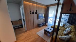 uma vista para uma sala de estar com um sofá e um quarto com janelas em Divcigora Apartman E&N em Divčibare