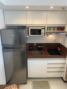 a kitchen with a stainless steel refrigerator and a microwave at Dunas de Cotovelo in Parnamirim