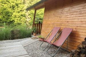 2 chaises assises sur une terrasse en bois à côté d'un bâtiment dans l'établissement Zoo park Ranč Aladin - Glamping apartment, à Mirna