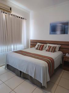 a bedroom with a large bed and a window at Hotel Estrela Mares in Três Marias