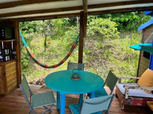 una mesa y sillas en un porche con hamaca en Bungalow avec vue dans lieu calme en Le Carbet