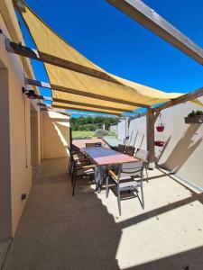 een patio met een tafel en stoelen onder een luifel bij L'Ouvéa joli gîte à 10 min du parc le Puy du Fou in Sevremont