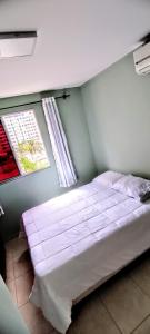 a bed in a room with a window and a bedvisor at Apartamento Aconchegante in Goiânia