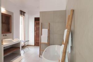 uma casa de banho com uma banheira branca e um lavatório. em Zanzibar White Sand Luxury Villas & Spa - Relais & Chateaux em Paje