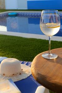 una copa de vino sentada en una mesa con un sombrero en Quinta Ribeirinha - Lagos, en Bensafrim