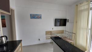 a kitchen with a black counter top and a tv on the wall at Apto 2 Quartos com Ar a 200m da Praia in Florianópolis