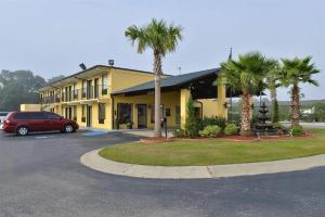 a yellow building with palm trees in a parking lot at Americas Best Value Inn Saint George in Saint George