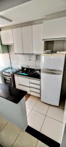 a kitchen with white cabinets and a white refrigerator at Apartamento Aconchegante in Goiânia