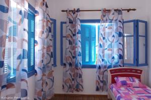 a bedroom with blue and white curtains and a bed at Garden house in Amarynthos