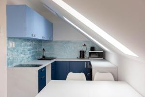 eine Küche mit blauen und weißen Schränken und einem Waschbecken in der Unterkunft Ahoy Relax Apartmán Ocean in Nesvady