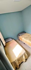two beds in a room with a blue wall at Apartamento Aconchegante in Goiânia