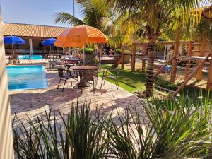 a patio with tables and chairs next to a pool at Hotel Pousada Parque das Águas in Olímpia