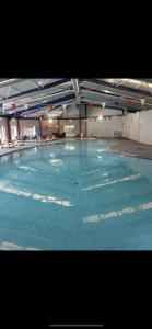 a large swimming pool with blue water in a building at Pendle Hill View in Preston