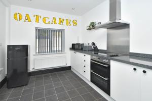 a kitchen with white cabinets and a black refrigerator at Potter's Rest by YourStays in Stoke on Trent