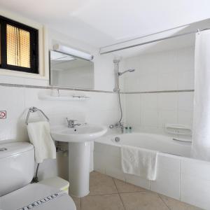 a white bathroom with a sink and a bath tub at Club Aphrodite in Erimi
